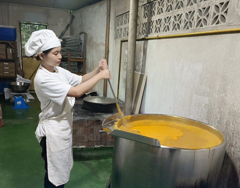 A cook in whites stirring a vat of mango purée in the farm’s own processing kitchen