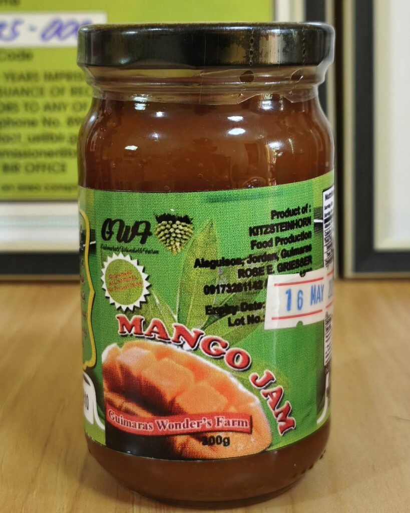 A 100 g round jar of Guimaras Wonder’s Farm mango jam, its green label naming Kitzsteinhorn Food Production in Alaguisoc, Jordan.